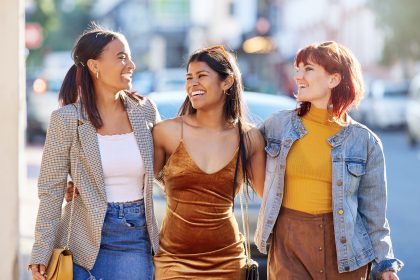 3 women walking arm in arm in unique attire